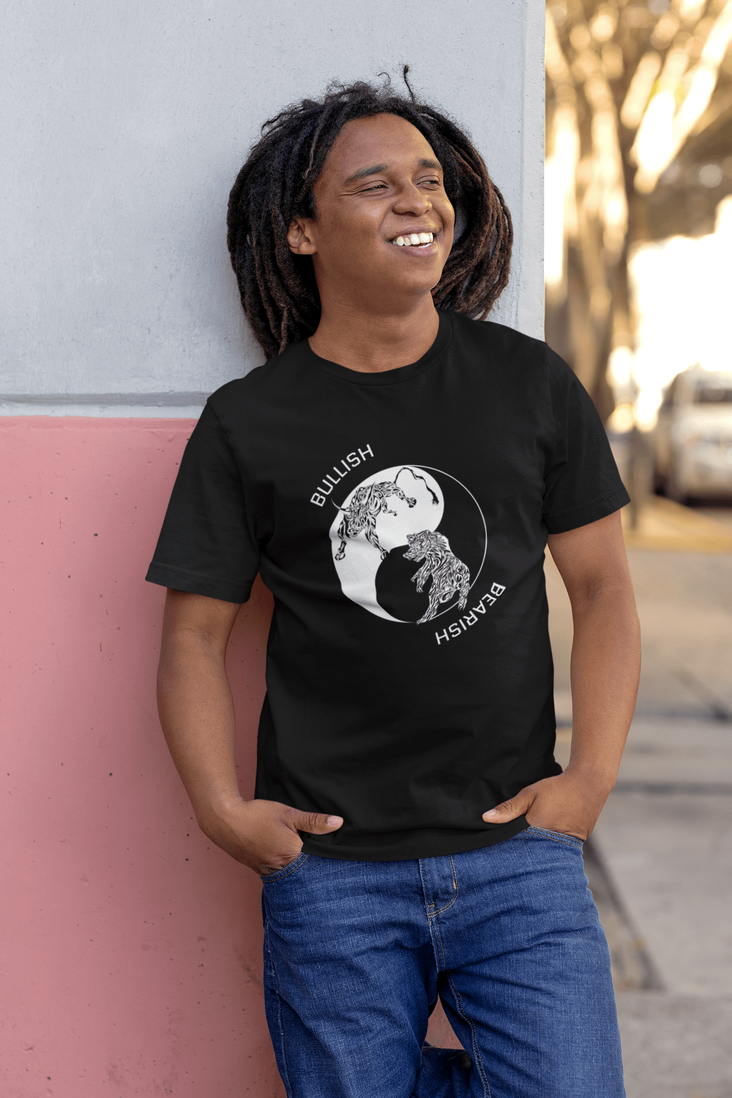 Happy man leaning against a wall wearing our Bullish/Bearish - Yin Yang - Tribal design on a black t-shirt.